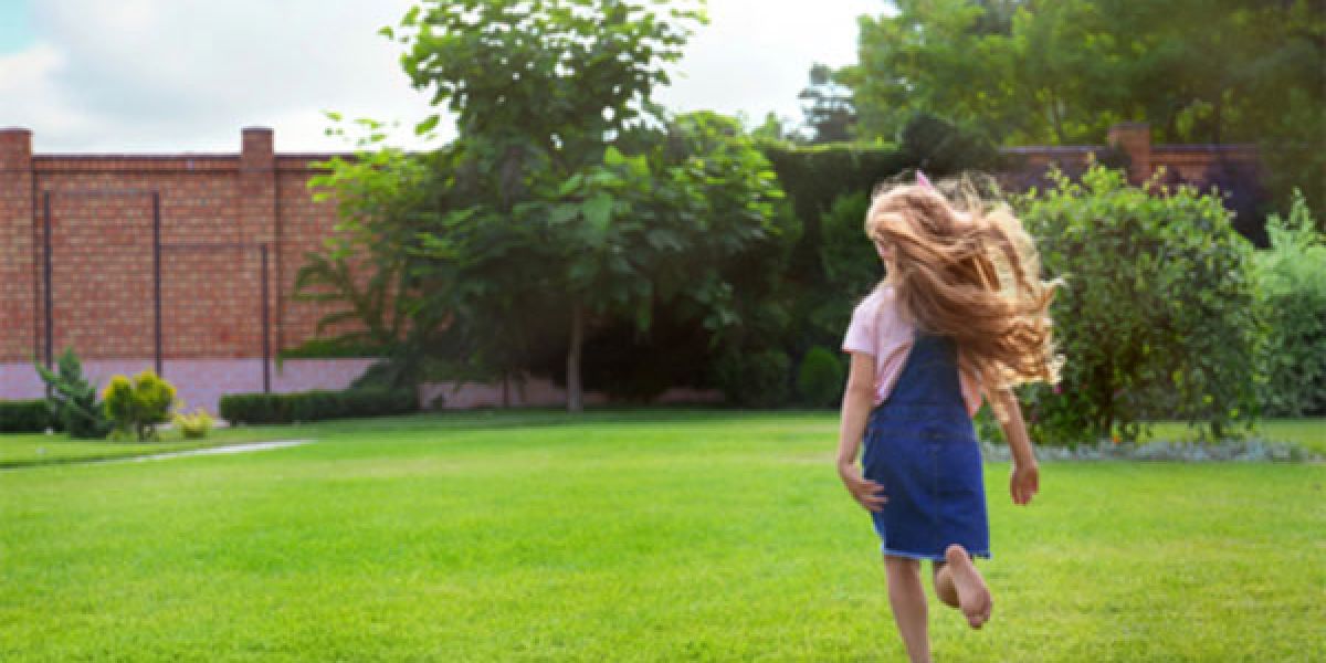 Young girl running on a manicured lawn.