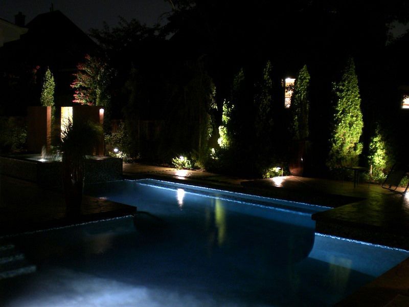Pool with landscape lighting at night.