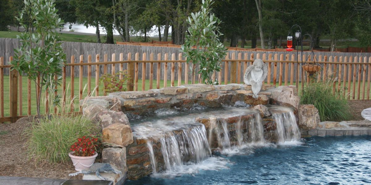 Beautiful waterfall over stone into swimming pool.