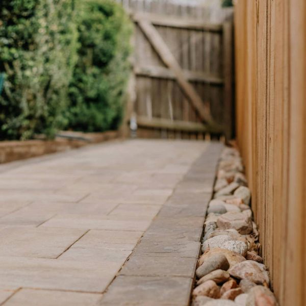 A custom paver walkway with a pebble stone french drain on the edges.