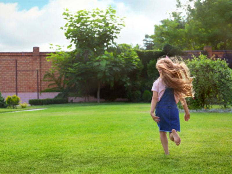 Young girl running on a manicured lawn.